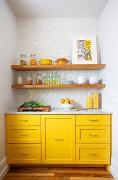 a kitchen with yellow cabinets and white walls