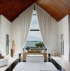 a living room filled with white furniture and large windows overlooking the ocean on a sunny day