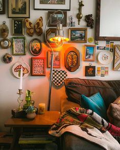 a living room filled with lots of framed pictures and art on the wall above a couch