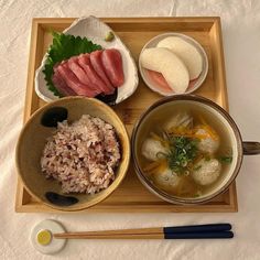 a wooden tray topped with bowls filled with different types of food next to chopsticks