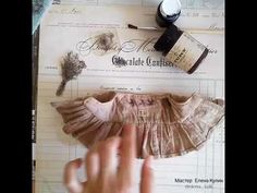 someone is holding their hand over an old doll's dress on top of papers