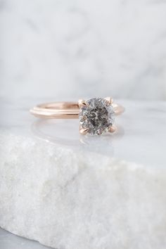 an engagement ring on top of a white marble slab with a diamond in the center