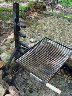 an outdoor bbq grill on the ground with rocks and trees in the backgroud