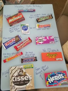 a table topped with lots of candy on top of a blue board covered in writing