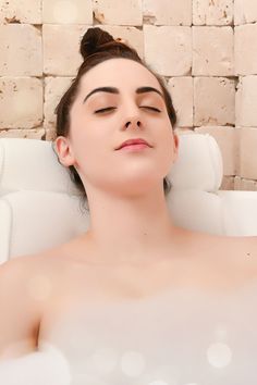 a woman laying down in a bathtub with her eyes closed and one eye closed