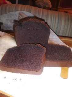 three pieces of brown bread sitting on top of a cutting board next to a couch