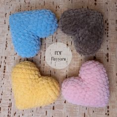 four small knitted hearts sitting on top of a table