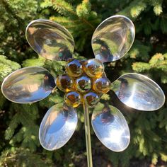 a close up of a flower made out of glass balls with trees in the background