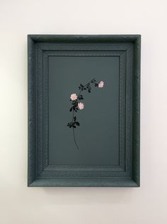 a black frame with pink flowers hanging on the wall