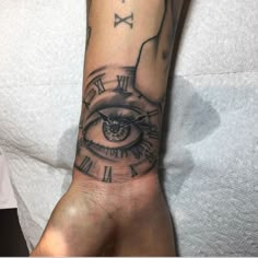 a hand with a clock and eye tattoo on it