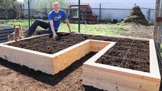 a man kneeling down next to two raised beds with dirt on the ground in front of him