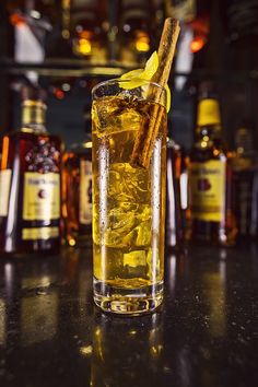 a tall glass filled with ice and cinnamon on top of a table next to bottles