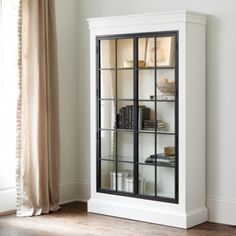 a white bookcase with glass doors in a living room