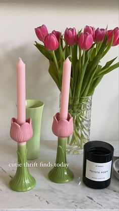 some pink flowers are in vases and candles