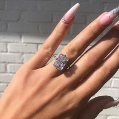 a woman's hand with pink and white nail polish holding an engagement ring on her finger