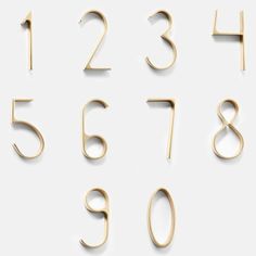 gold numbers and numerals are arranged on a white surface, with one number in the middle