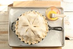 an uncooked pie sitting on top of a pan next to a measuring cup