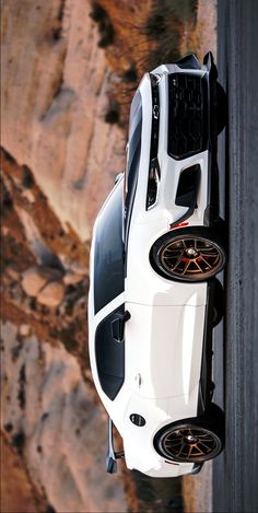 a white car parked on the side of a road next to a rocky mountain range