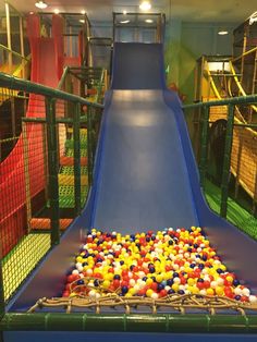 an indoor play area with a slide and colorful balls on the ground in front of it