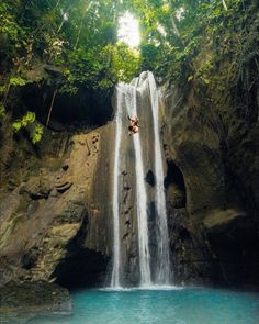 a man is hanging off the side of a waterfall