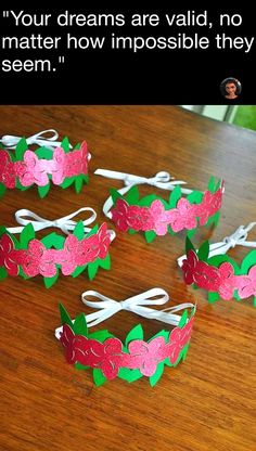 four paper crowns sitting on top of a wooden table next to an image of a woman's face