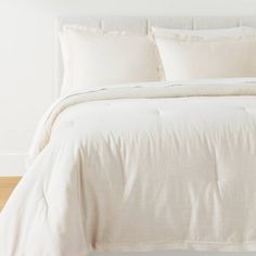 a bed with white sheets and pillows in a room