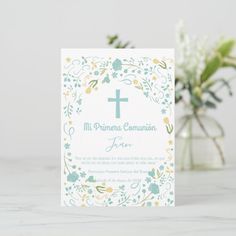 a white card with a cross on it and some flowers in front of the card