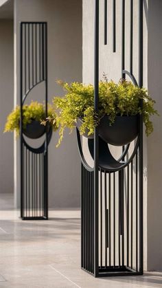 two black metal planters with plants in them