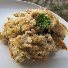 a white plate topped with food covered in sauce and garnished with a green sprig