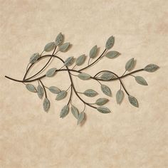 a metal branch with leaves on it is mounted to the side of a beige wall