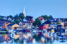 a harbor filled with lots of boats next to tall buildings and a steeple in the background