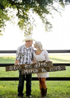 a man and woman holding a sign that says save the date