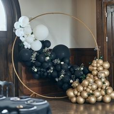 black and gold balloons are arranged in a circle on the floor next to a table