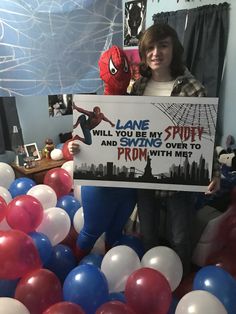 a woman holding up a sign with balloons around her and spider man in the background