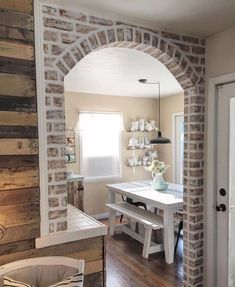 an arch in the wall leads into a dining room with a table and chairs on it