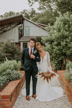 a bride and groom posing for a photo in front of a house with greenery