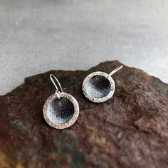 These silver earrings are made of two separate components, a fine silver (.999) textured domed disc and a sterling silver (.925) textured open circle. The domed disc is oxidised to contrast beautifully with the open circle which is not oxidised.  Handmade sterling silver earwires. Perfect for everyday wear. Diameter is approximately 1.7cm/ 0.66inch. I have 2 pairs available for the moment, so you may or may not receive the pair photographed. There may be small differences between the 2 pairs due Silver Round Earrings As Gift, Silver Rounded Earrings As Gift, Silver Round Earrings For Gift, Silver Rounded Earrings For Gifting, Silver Hammered Circle Earrings, Silver Hammered Round Earrings, Hammered Silver Round Disc Earrings, Silver Hammered Open Circle Earrings, Hammered Silver Circle Earrings