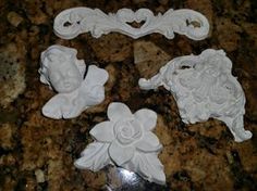 four white flowers are sitting on a granite counter top, and one is made out of clay