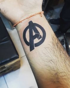 a man's arm with an avengers symbol tattoo on it