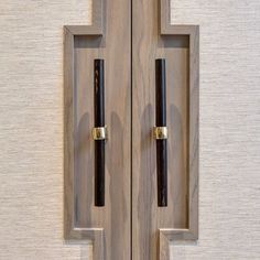 two wooden doors with black handles on each side and one has a pen in the middle