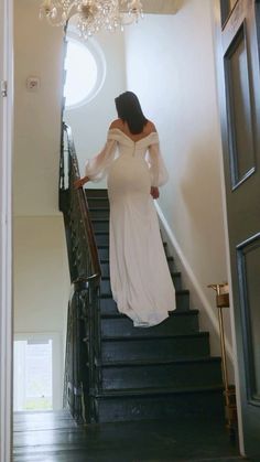 a woman in a white dress is walking down the stairs with her hands on her hips