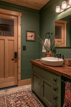 a bathroom with green walls and wood accents, including a large mirror over the sink