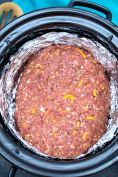 an open crock pot filled with ground beef and seasoning sitting on top of a table