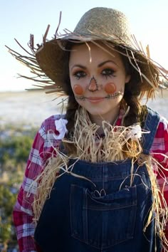 a woman with makeup on her face and nose is standing in the grass wearing a straw hat