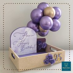 purple and gold balloons are in a box with a sign that says america happy birthday