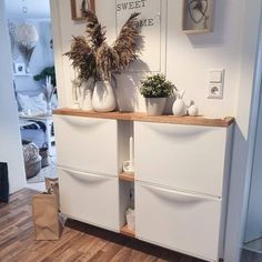 two white vases sitting on top of a wooden shelf in front of a door