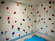 there is a climbing wall in the room with many different colored rocks and shapes on it