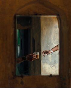 two people reaching out their hands to touch each other in front of a wooden door