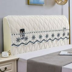 an upholstered headboard on a bed in a room with white walls and furniture