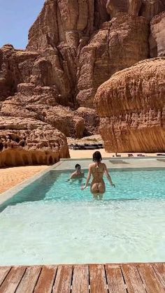 two people are playing in the pool near some mountains